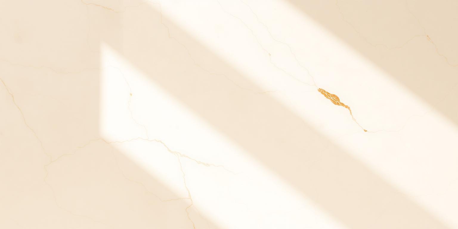 Mármore ivory atravessado por um feixe suave de luz natural, com veios bronze delicados — atmosfera serena que convida ao próximo passo do cuidado.